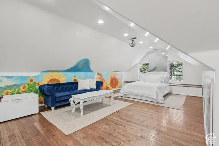 Vaulted ceilings with recessed lighting, wood-finish flooring, and built-in shelving