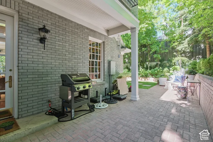 Brick exterior with a covered patio, paved hardscaping, and verdant landscaping