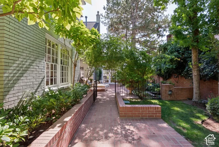 Brick exterior, mature trees, manicured landscaping, brick pathway, and wrought iron fencing