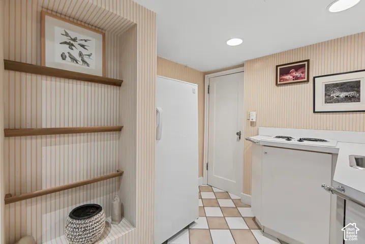 Built-in shelving, recessed lighting, checkerboard floor tiling, and a built-in cooktop