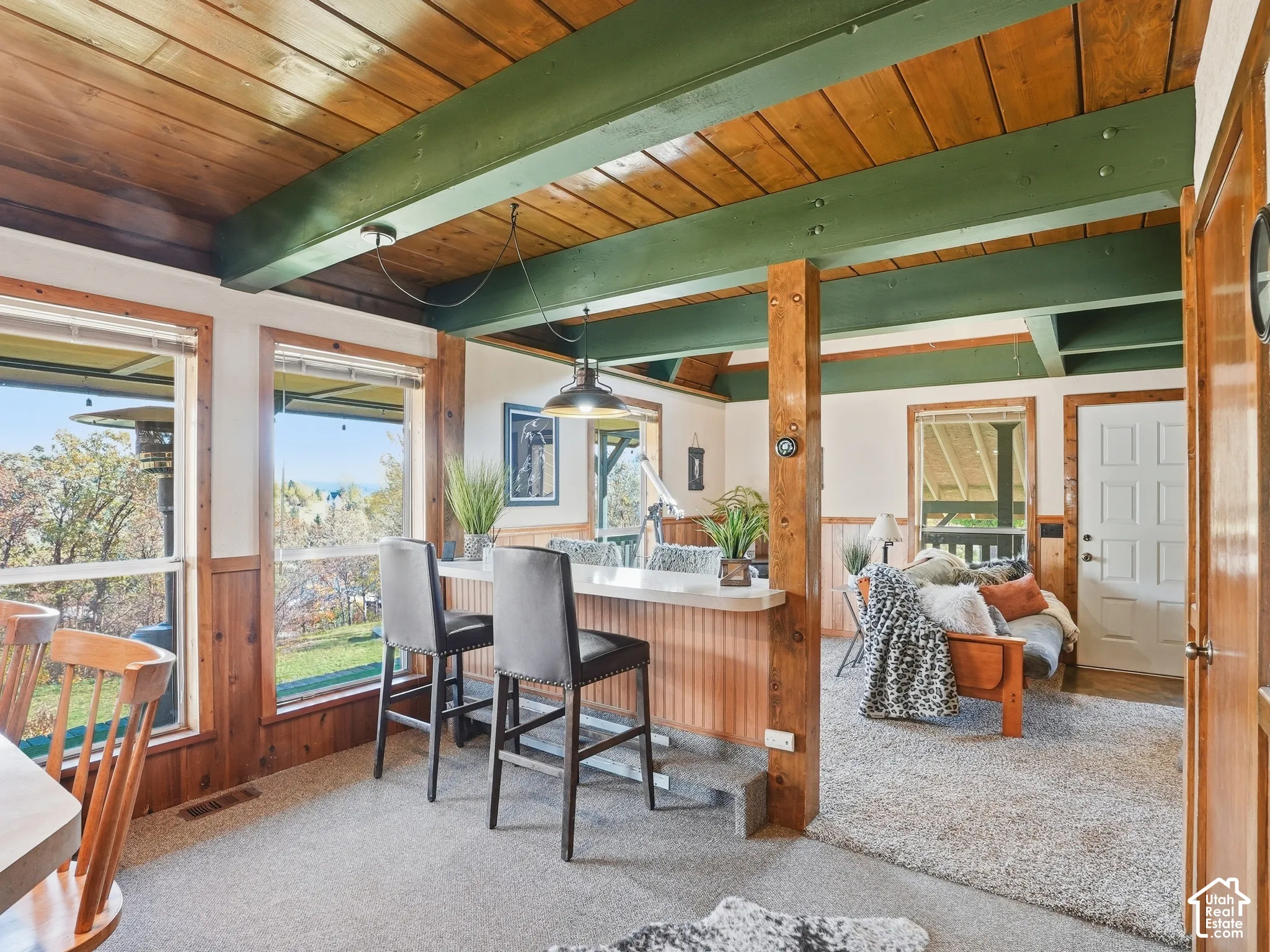 Wood-plank ceiling with exposed painted structural beams, wood wainscoting, and a built-in counter