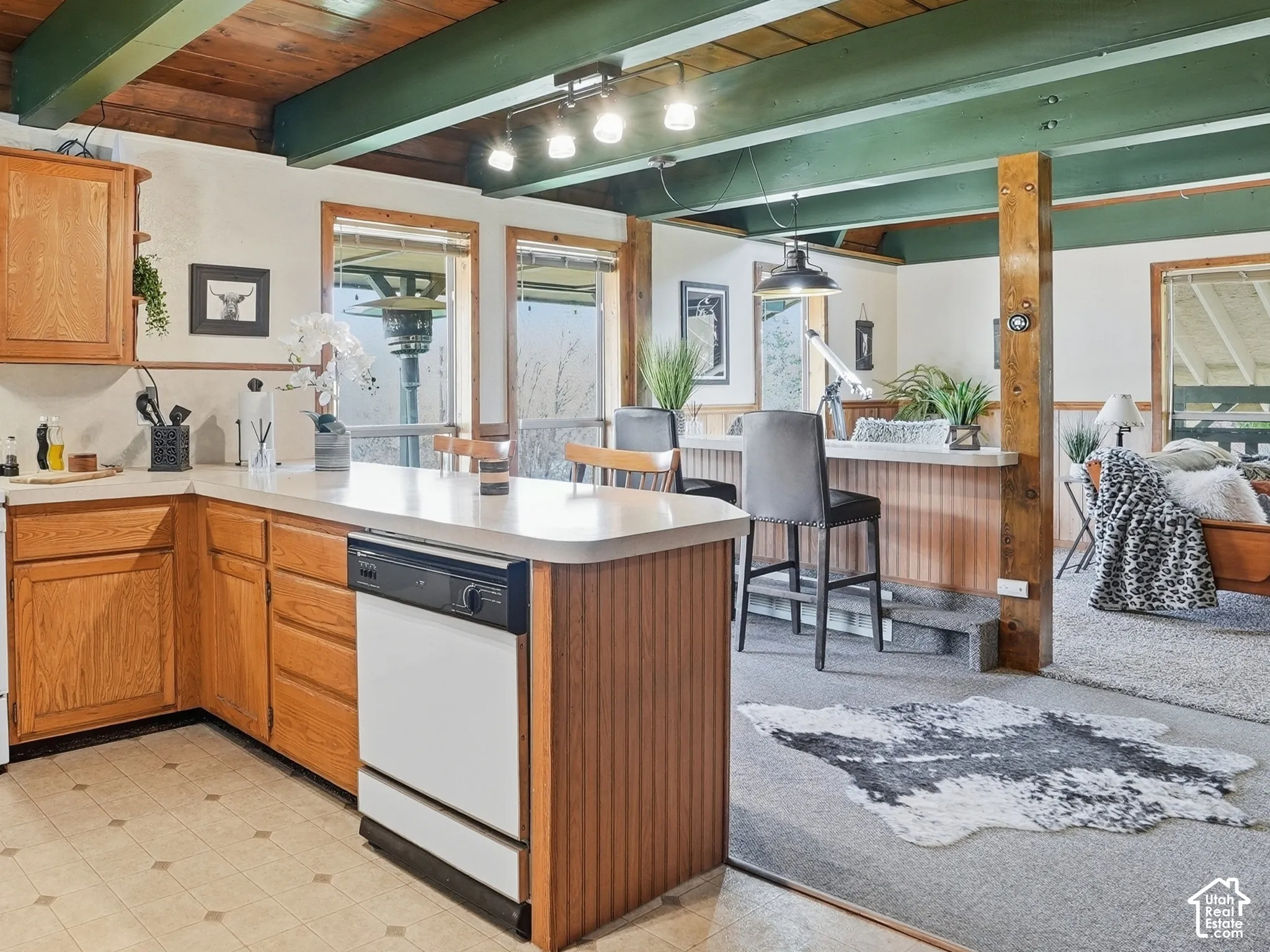 Kitchen featuring wood cabinetry, solid-surface countertops, exposed wood-plank ceiling with painted beams, and track lighting