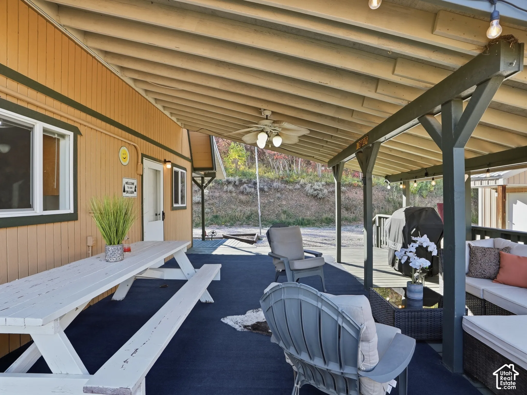 Covered outdoor deck featuring exposed beam ceilings, a mounted ceiling fan, and structural support posts