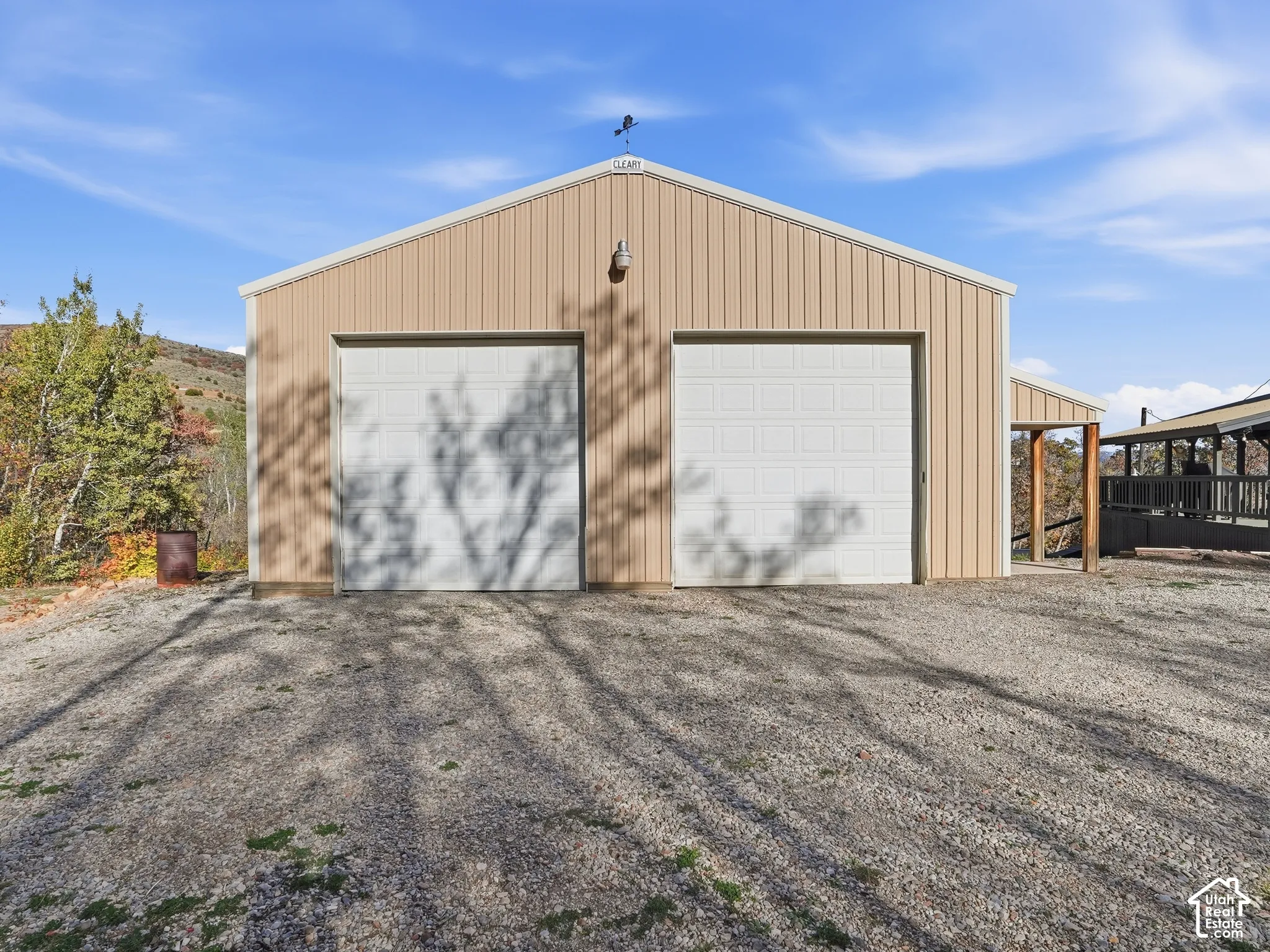 Detached workshop featuring vertical metal siding, two overhead garage doors, a gabled roofline, and an exterior light fixture
