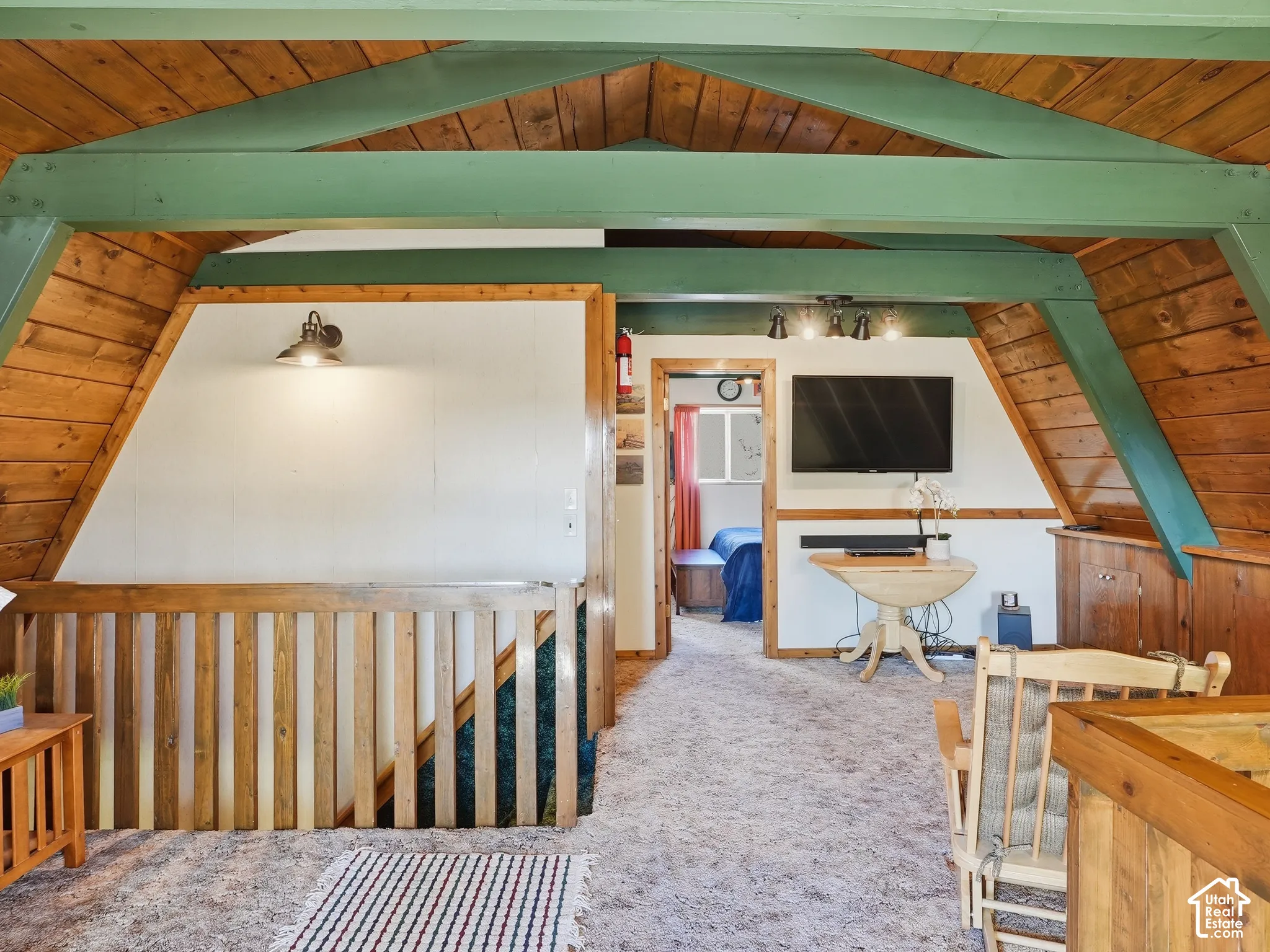 Vaulted ceilings with exposed timber beams, natural wood-paneled walls, interior wooden railings, and integrated wall-mounted lighting
