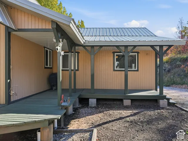 Covered porch with vertical wood-finish siding, metal roofing, and exposed timber support posts