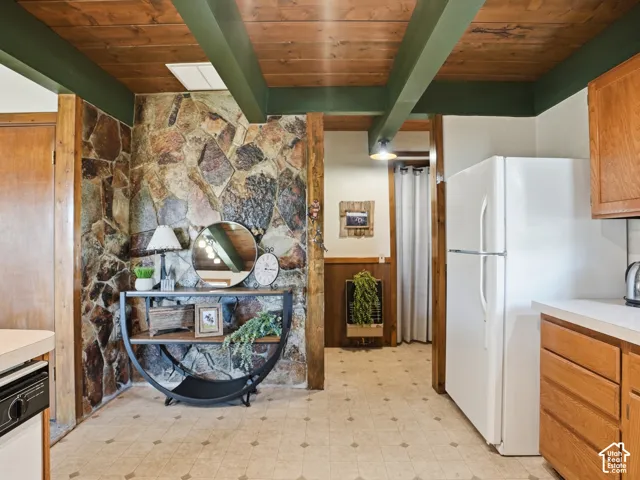 Interior featuring natural stone accent wall, wood-plank ceiling with exposed beams, and built-in wood cabinetry