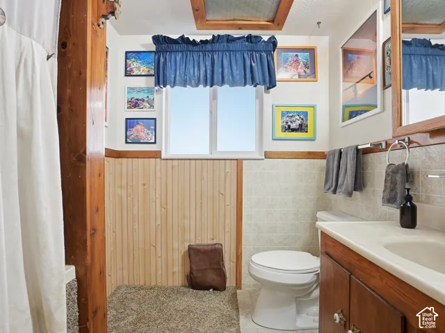 Bathroom featuring wood paneling, a wooden vanity with an integrated basin, a window with natural light, and tiled wall accents