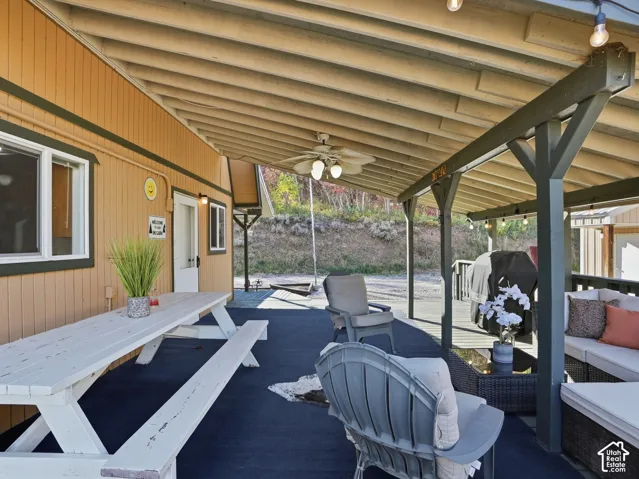 Covered outdoor deck featuring exposed beam ceilings, a mounted ceiling fan, and structural support posts