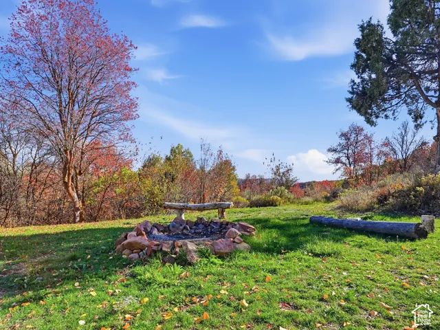 Outdoor grounds featuring a natural stone fire pit, wood log seating, and mature trees