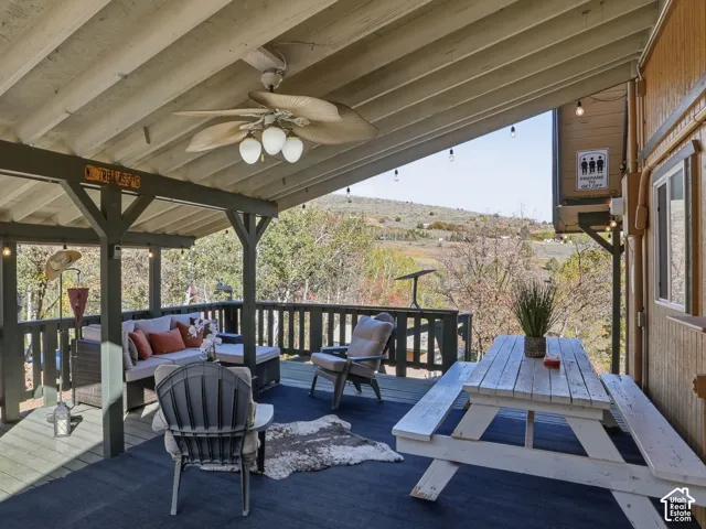 Covered deck featuring exposed beam ceiling, ceiling fan, and wooden balustrade