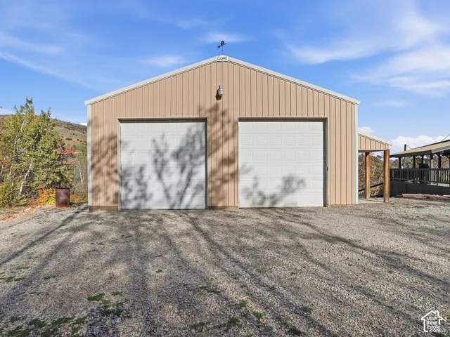 Detached workshop featuring vertical metal siding, two overhead garage doors, a gabled roofline, and an exterior light fixture