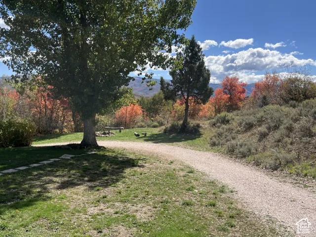 Expansive outdoor space featuring a gravel pathway, mature trees, natural landscaping, and distant mountains