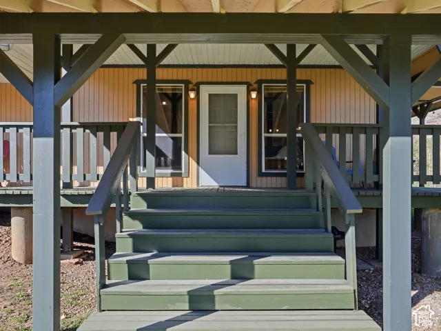 Covered wooden front porch with stairs, vertical siding, and exterior wall-mounted light fixtures