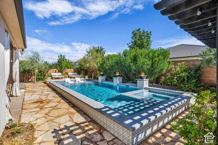 Outdoor living space featuring a custom pool with integrated spa, flagstone patio, and a pergola