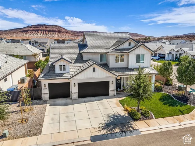 Stunning two-story residence featuring a sophisticated cream exterior with architectural detail, dual-bay garage with dark panel doors, and mature landscaping anchored by a specimen tree