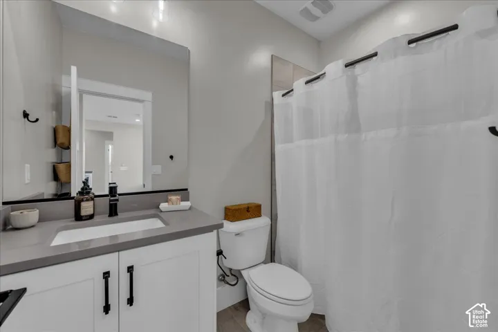 White vanity with matte black hardware, integrated rectangular sink, gray countertop, and an expansive wall-mounted mirror