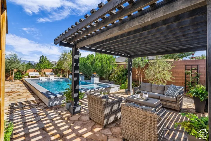 Expansive outdoor space featuring a dark-stained wood pergola, flagstone patio, swimming pool, and built-in spa