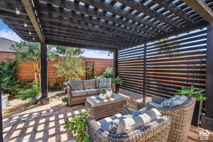 Covered patio featuring a dark wood pergola with string lighting and a slatted privacy screen