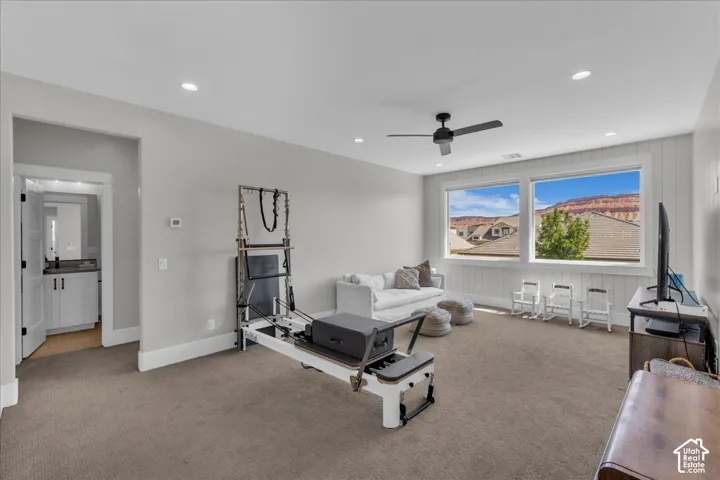 Recessed lighting, ceiling fan, carpeting, dual windows with surrounding scenery, and a separate room with a vanity