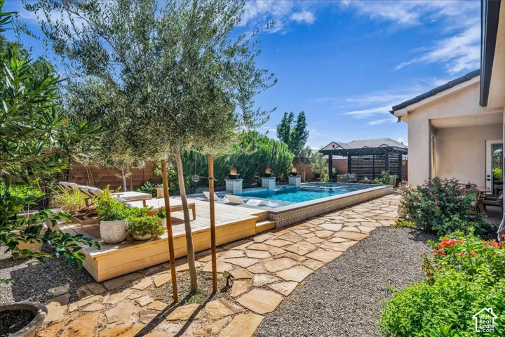 Swimming pool with decorative tile surround, adjacent wooden deck, flagstone pathway, and landscaping