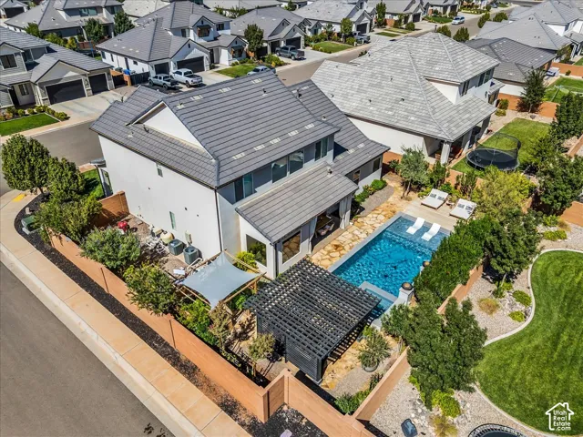 Backyard oasis featuring a rectangular swimming pool, stone paver patio, and a shaded pergola