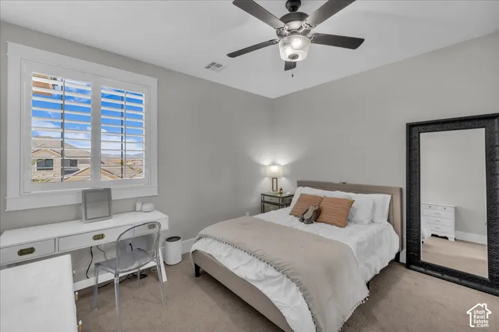 Window with white plantation shutters, ceiling fan with light fixture, gray wall paint, and carpeted flooring
