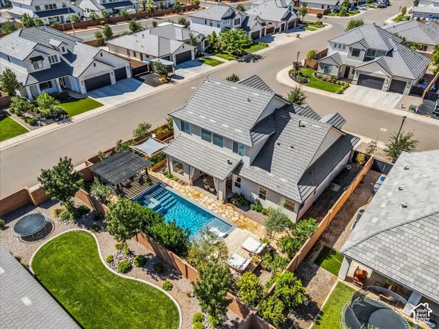 Contemporary residential architecture with a multi-level roofline, a private pool area with a dark pergola, and a manicured lawn