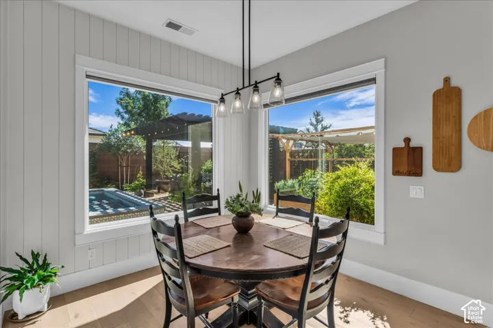 Corner windows with natural light, wood-finish flooring, and a modern linear chandelier