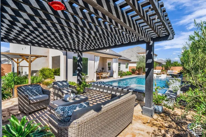 Expansive backyard featuring a dark wood pergola, stone patio, built-in swimming pool, and mature landscaping