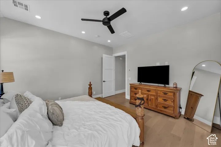 Spacious bedroom featuring hardwood flooring, recessed lighting, and a ceiling fan
