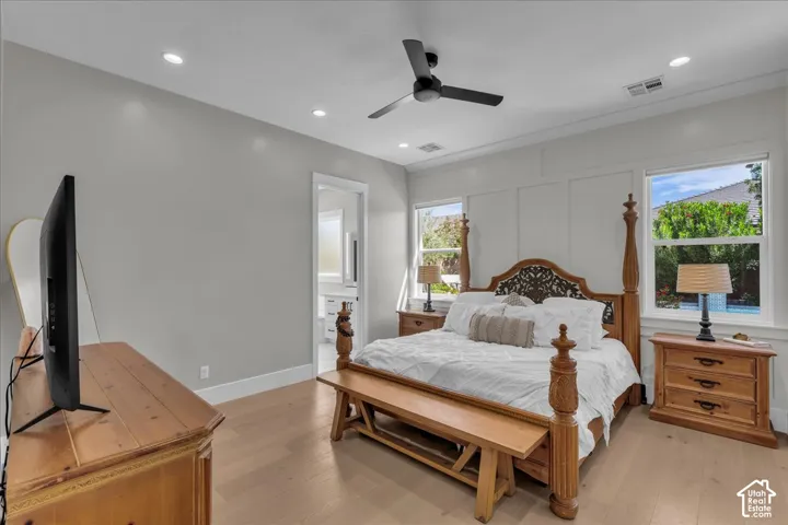 Recessed ceiling lighting, wood-finish flooring, ceiling fan, white paneled wall detail, and an en-suite bathroom