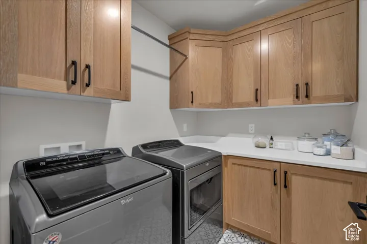 Light wood-finish cabinetry, white solid surface countertops, and patterned floor tile