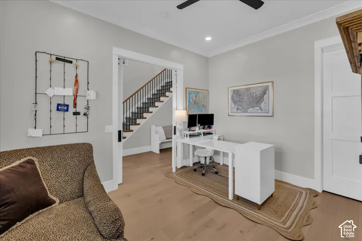 Bright, open home office featuring a white desk with built-in storage, recessed ceiling lighting, and ceiling fan