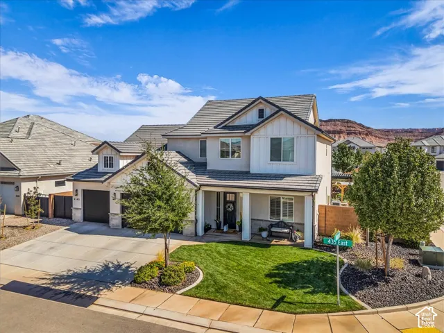 Two-story residence featuring a stone and stucco exterior, dark shingle roofing, an attached two-car garage, and a concrete driveway