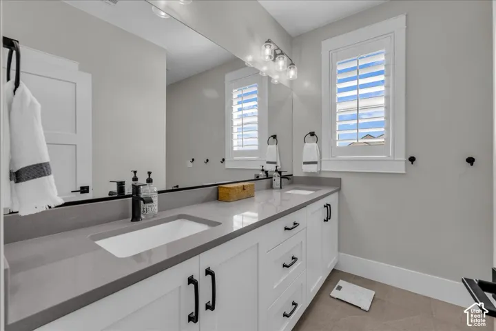 Dual vanity with integrated sinks, gray countertops, white shaker-style cabinetry, and matte black hardware