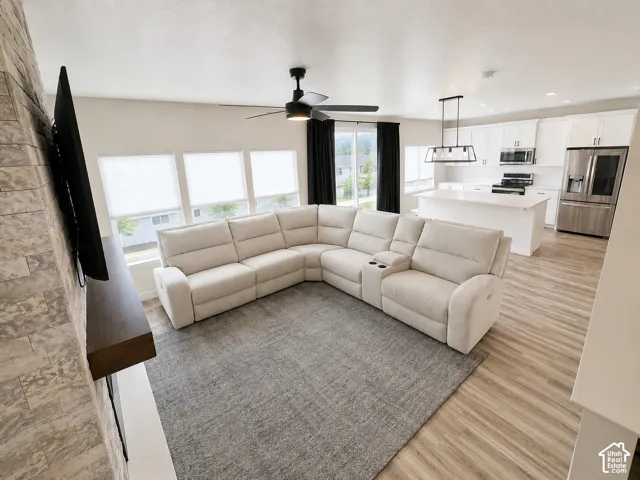 Open-concept living space featuring wood-finish flooring, a contemporary ceiling fan, and multiple windows