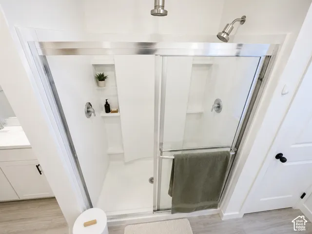 Shower enclosure with sliding glass door, brushed nickel fixtures, built-in shelving, and a rain showerhead