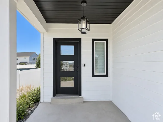 Covered concrete porch with white siding and a black front door