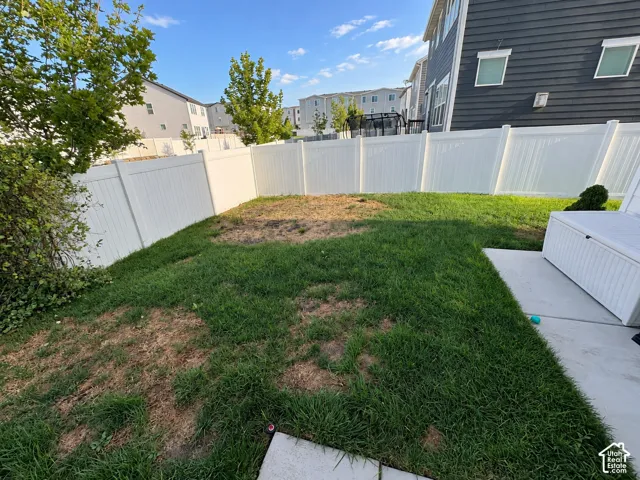 Expansive backyard featuring a white vinyl privacy fence and a concrete patio