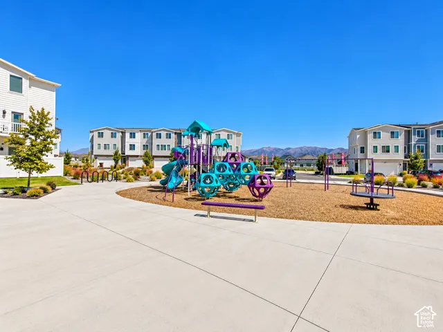 Community playground featuring multiple play structures, a merry-go-round, and benches on a wood chip surface