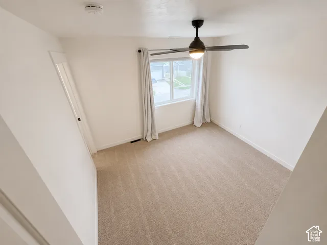 Neutral-toned wall-to-wall carpeting, white painted walls, and a modern ceiling fan with integrated lighting
