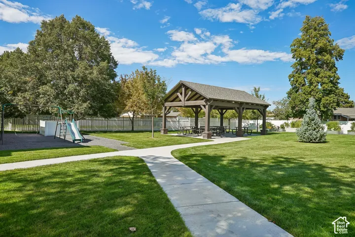Expansive green space featuring a covered pavilion, paved pathways, and a dedicated playground area