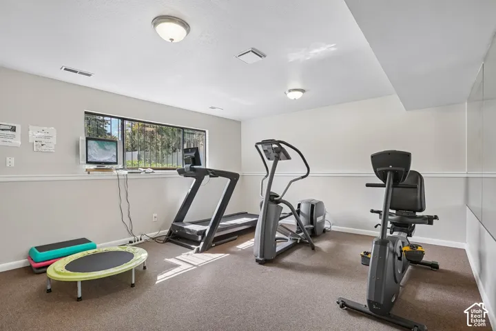 Recessed ceiling lights illuminate the carpeted floor and painted walls, complemented by a window with a security grates and a reflective wall panel