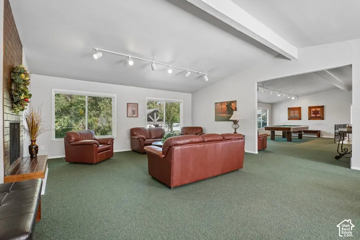 Spacious common area featuring vaulted ceilings, track lighting, a brick-front fireplace, and large windows