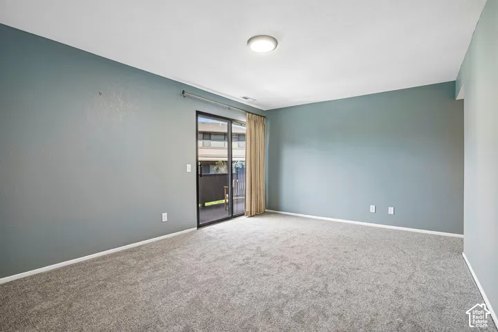 Grey carpet flooring with a sliding glass door and overhead lighting