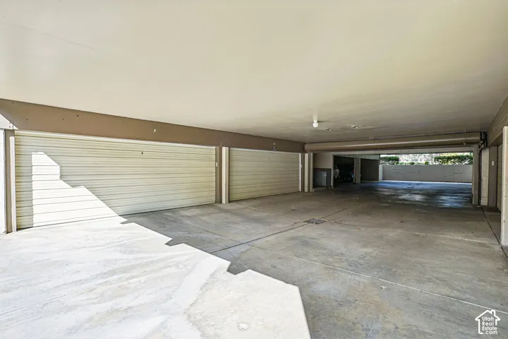 Covered parking structure with multiple garage door entries and concrete flooring