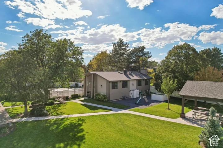 Expansive grounds featuring a manicured lawn, paved pathways, mature trees, and a covered outdoor structure