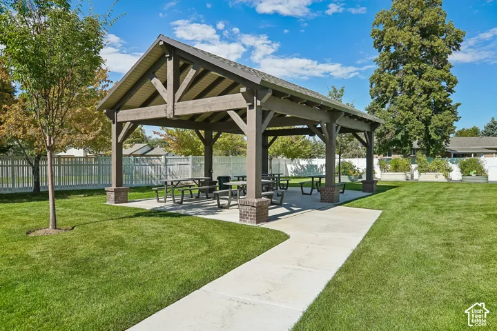 Expansive community lawn with a covered pavilion featuring exposed beam construction and brick-clad supports