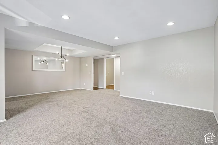 Recessed lighting, tray ceiling with contemporary chandelier, neutral wall tones, and light-toned carpeting